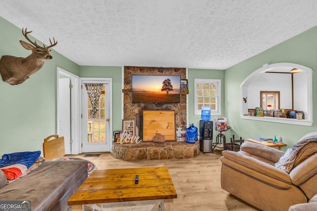 living room featuring a fireplace, a textured ceiling, and light wood-type flooring