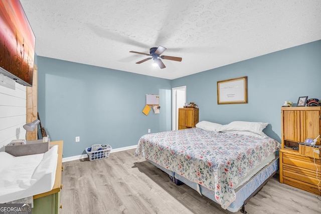 bedroom with ceiling fan, light hardwood / wood-style flooring, and a textured ceiling