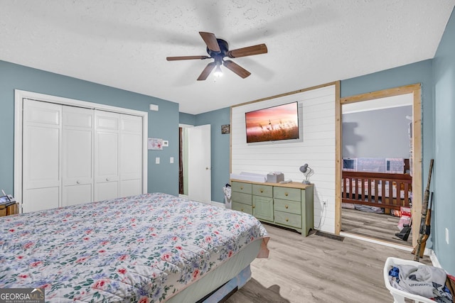 bedroom with ceiling fan, a textured ceiling, light hardwood / wood-style floors, and a closet