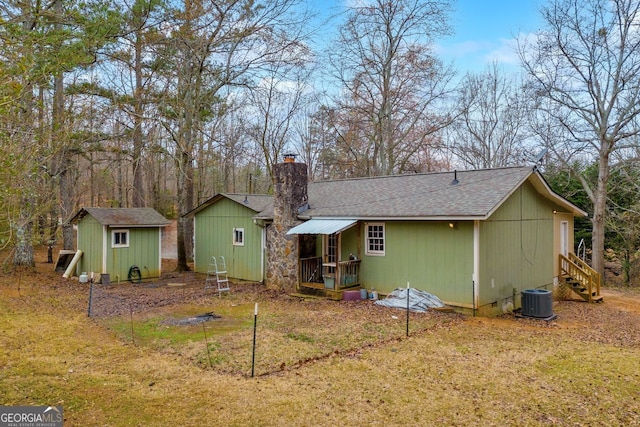 rear view of house with a shed, central AC, and a lawn