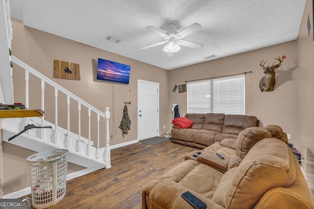 living room with dark hardwood / wood-style flooring, ceiling fan, and a textured ceiling