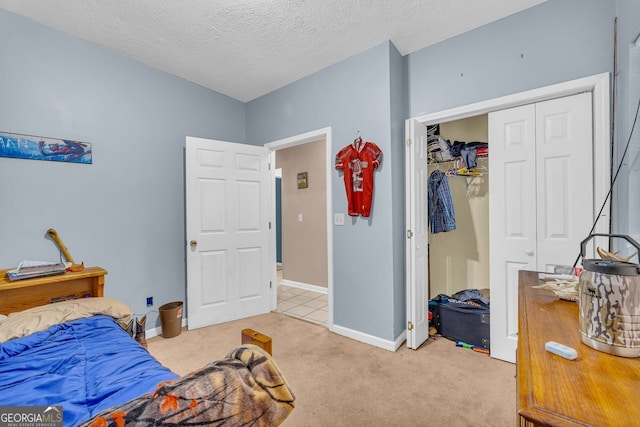 bedroom with a closet, light carpet, and a textured ceiling