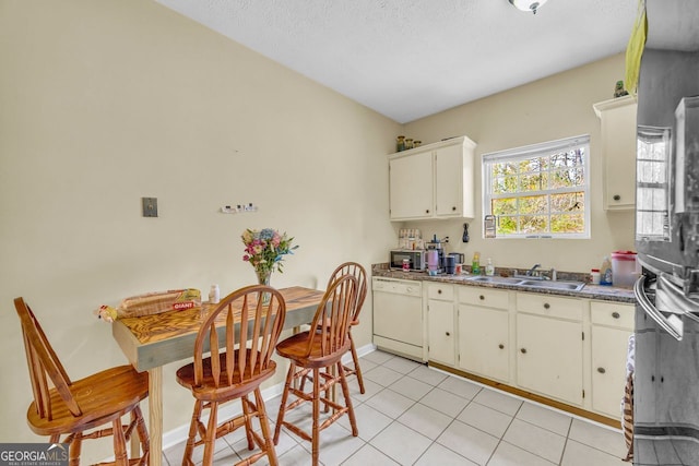 kitchen featuring sink, white cabinetry, a textured ceiling, light tile patterned floors, and dishwasher