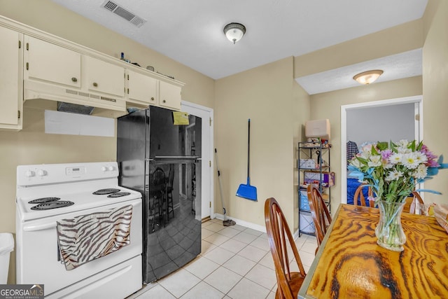 kitchen with black refrigerator, white range with electric cooktop, light tile patterned flooring, and white cabinets