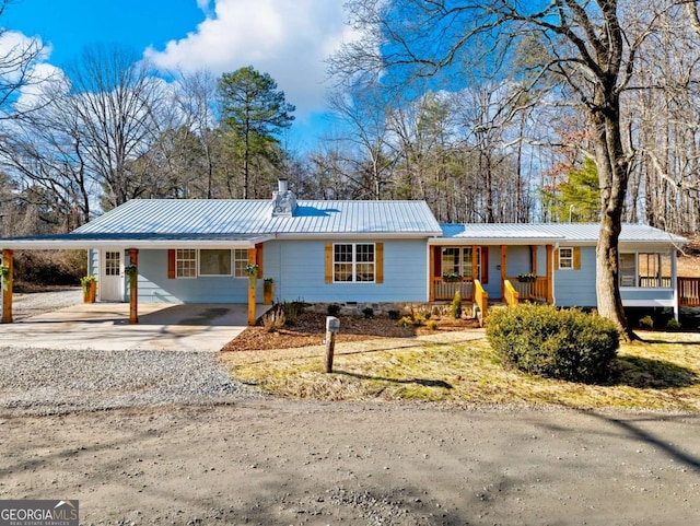 ranch-style home with concrete driveway, a chimney, metal roof, an attached carport, and a porch