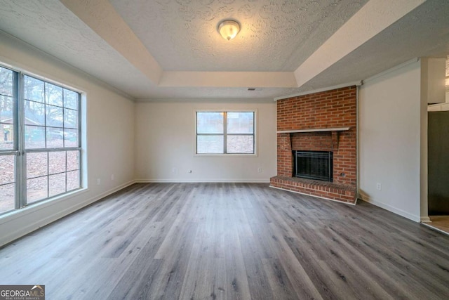 unfurnished living room featuring a fireplace, a raised ceiling, hardwood / wood-style floors, and a textured ceiling