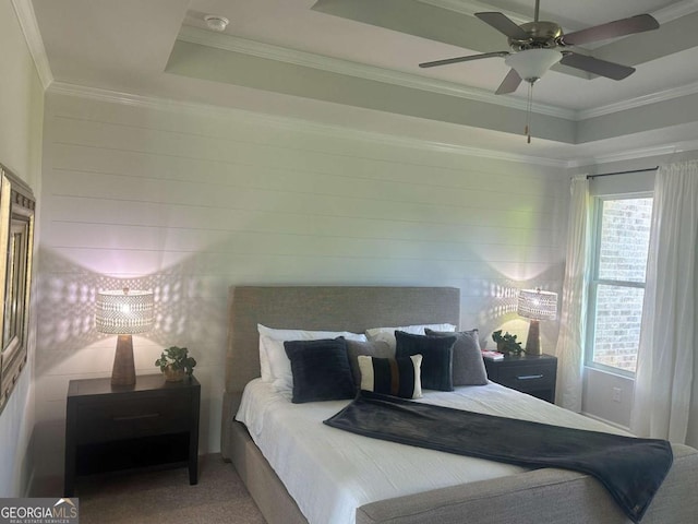 carpeted bedroom with ornamental molding, ceiling fan, and a tray ceiling