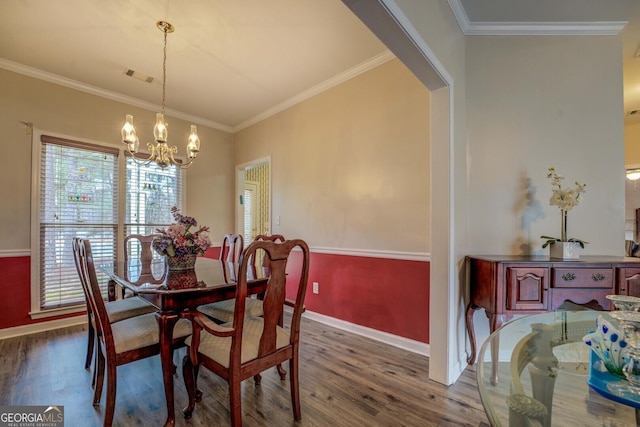 dining room with wood-type flooring, ornamental molding, and an inviting chandelier