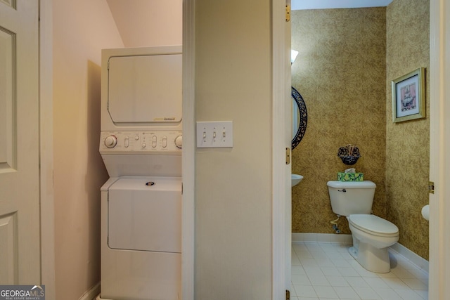 laundry room with stacked washer / dryer and light tile patterned floors