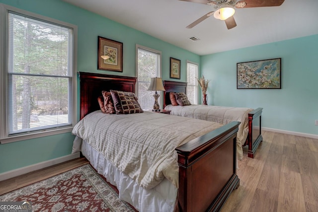 bedroom with multiple windows, ceiling fan, and light wood-type flooring