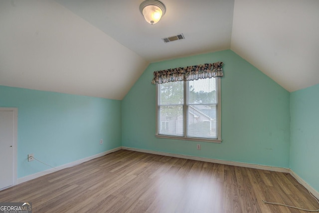 additional living space with hardwood / wood-style flooring and vaulted ceiling