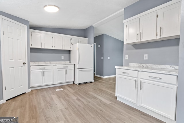 kitchen with white cabinetry, white fridge, lofted ceiling, and light wood-type flooring