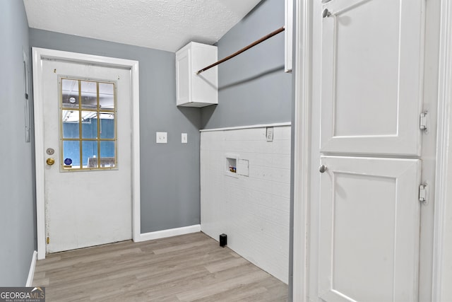 washroom with tile walls, cabinets, washer hookup, light hardwood / wood-style floors, and a textured ceiling