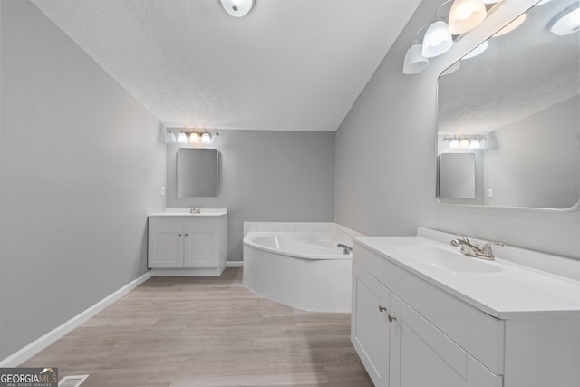 bathroom featuring vanity, a bathing tub, hardwood / wood-style floors, and a textured ceiling