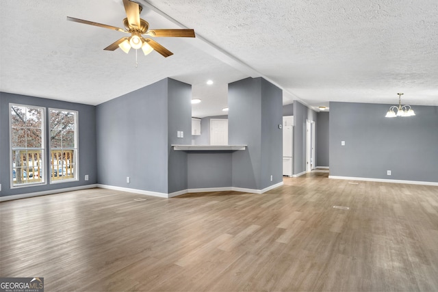 unfurnished living room with hardwood / wood-style flooring, ceiling fan with notable chandelier, and a textured ceiling