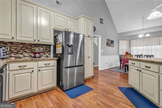 kitchen featuring pendant lighting, appliances with stainless steel finishes, light hardwood / wood-style floors, and cream cabinetry