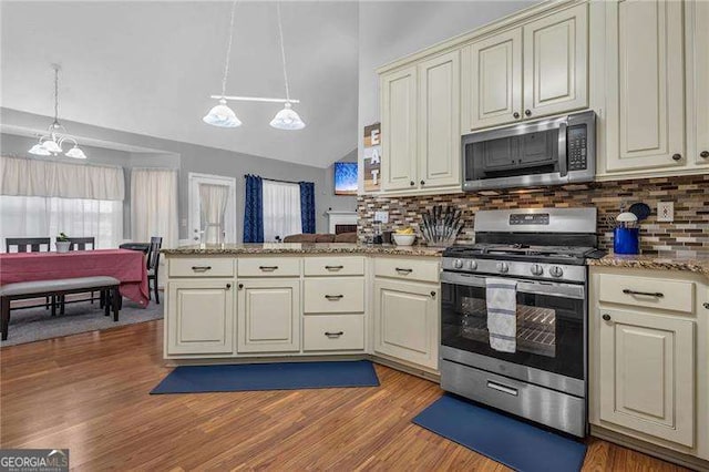 kitchen featuring cream cabinets, stainless steel appliances, hanging light fixtures, and kitchen peninsula