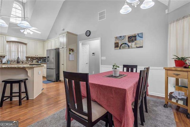 dining room featuring high vaulted ceiling, ceiling fan, and light wood-type flooring