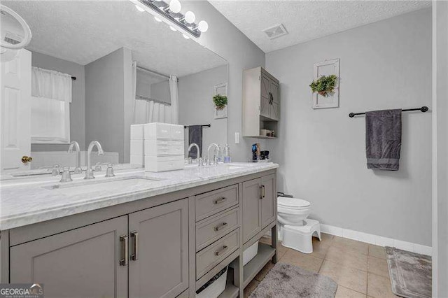 bathroom featuring tile patterned floors, vanity, toilet, and a textured ceiling