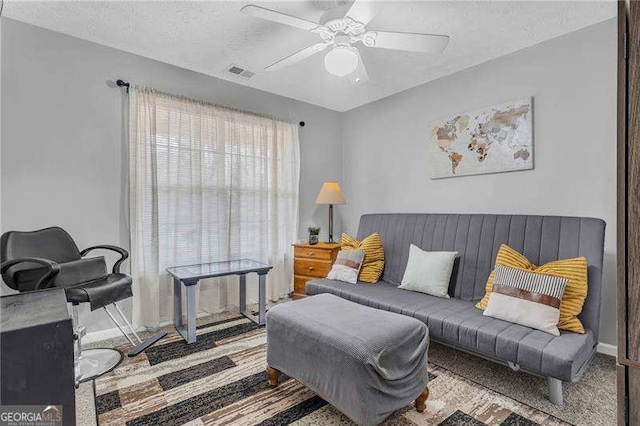 living room featuring ceiling fan and a textured ceiling