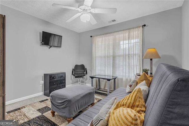 carpeted living room with a textured ceiling and ceiling fan