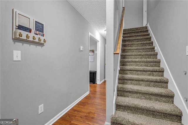 staircase with hardwood / wood-style floors and a textured ceiling