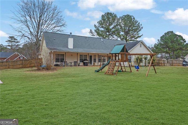 rear view of property with a yard and a playground