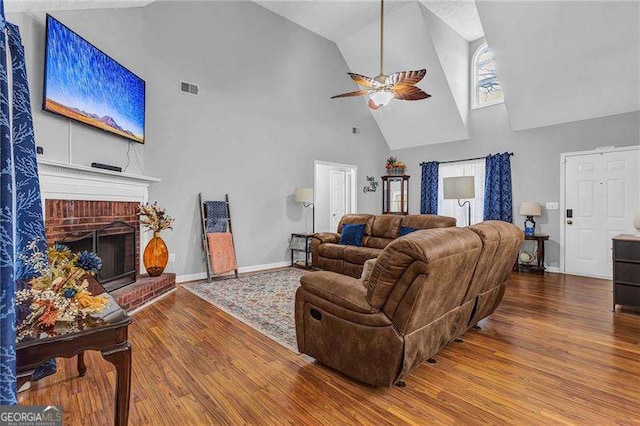 living room featuring ceiling fan, high vaulted ceiling, a fireplace, and hardwood / wood-style floors