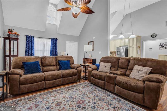 living room with hardwood / wood-style flooring, ceiling fan, and high vaulted ceiling