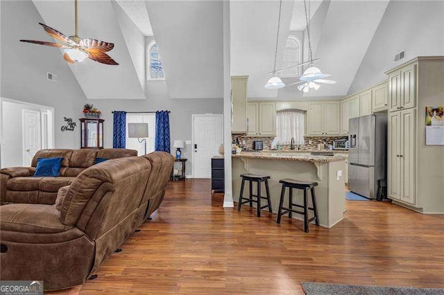 kitchen with pendant lighting, ceiling fan, a kitchen breakfast bar, stainless steel refrigerator with ice dispenser, and light stone countertops