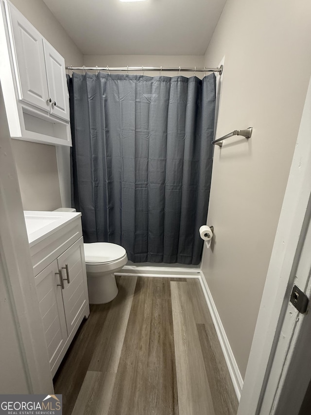 bathroom featuring wood-type flooring, curtained shower, vanity, and toilet