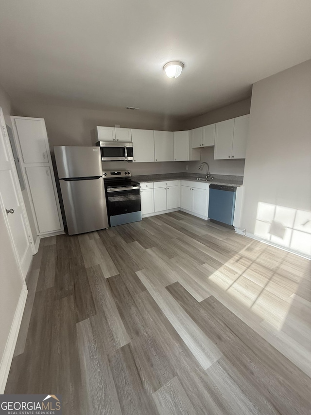 kitchen with sink, light hardwood / wood-style flooring, stainless steel appliances, and white cabinets