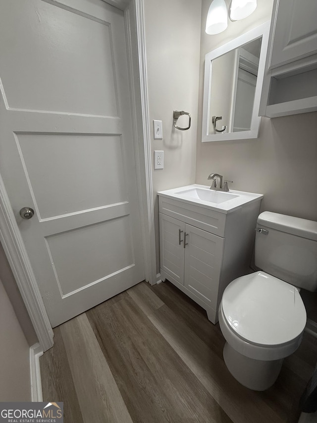 bathroom with wood-type flooring, vanity, and toilet