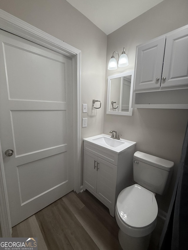 bathroom with wood-type flooring, toilet, and vanity