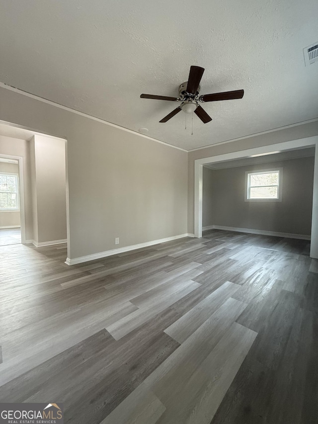 spare room featuring ceiling fan, a wealth of natural light, wood-type flooring, and a textured ceiling