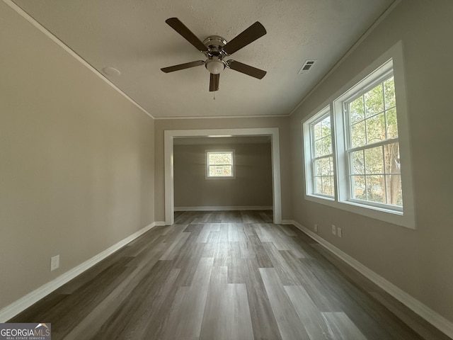 empty room featuring crown molding, ceiling fan, hardwood / wood-style floors, and a textured ceiling