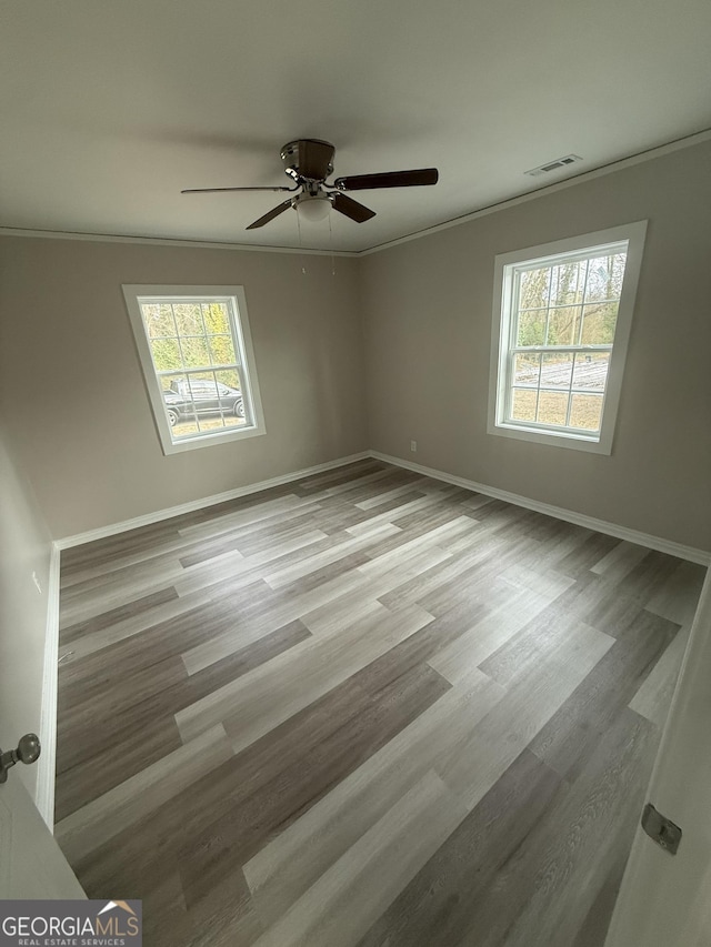 unfurnished room featuring crown molding, plenty of natural light, and light wood-type flooring