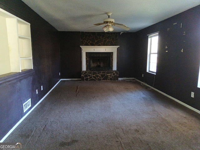 unfurnished living room with carpet floors, a fireplace, visible vents, a ceiling fan, and baseboards