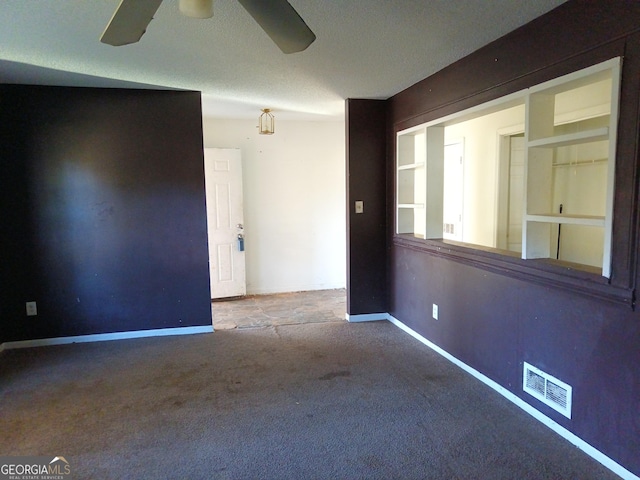 spare room featuring visible vents, baseboards, ceiling fan, a textured ceiling, and carpet floors