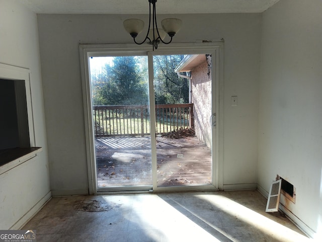 doorway to outside with a chandelier and baseboards