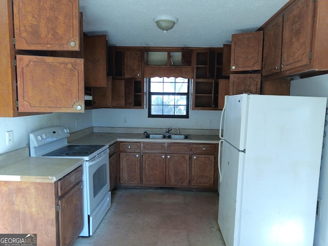 kitchen with white appliances, light countertops, a textured ceiling, open shelves, and a sink