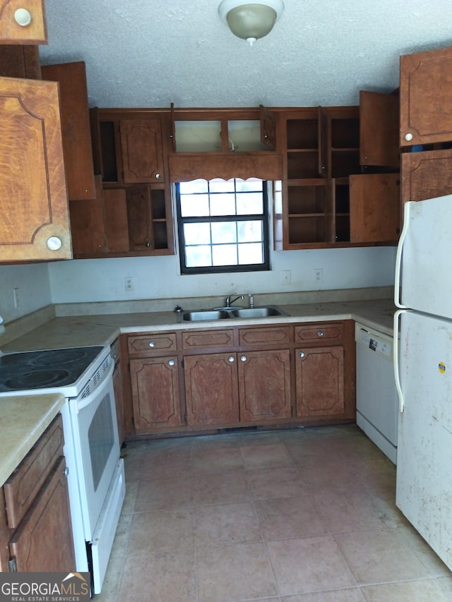 kitchen featuring white appliances, a sink, light countertops, brown cabinets, and open shelves