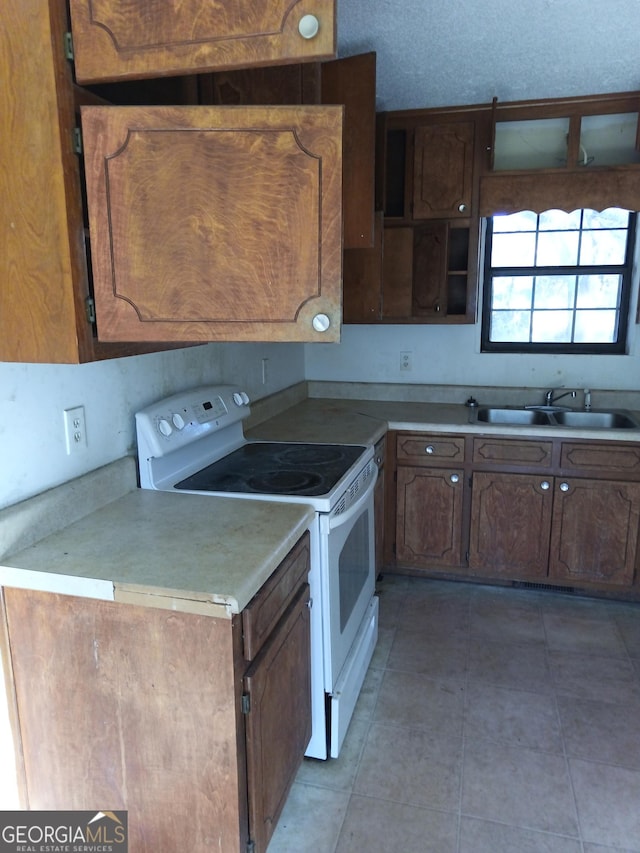 kitchen featuring white electric range oven, light countertops, a sink, a textured ceiling, and tile patterned flooring