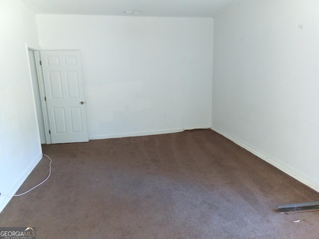 spare room with dark carpet, visible vents, and baseboards