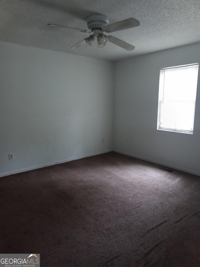 empty room with a textured ceiling, carpet flooring, a ceiling fan, and baseboards