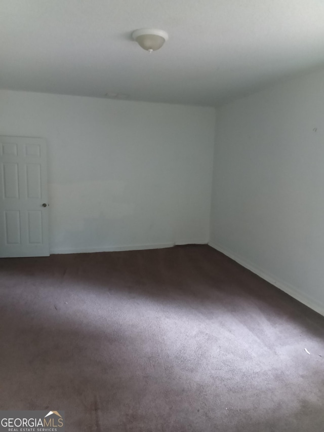 spare room with dark colored carpet