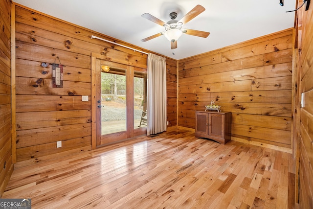 doorway to outside with ceiling fan, light hardwood / wood-style flooring, and wooden walls