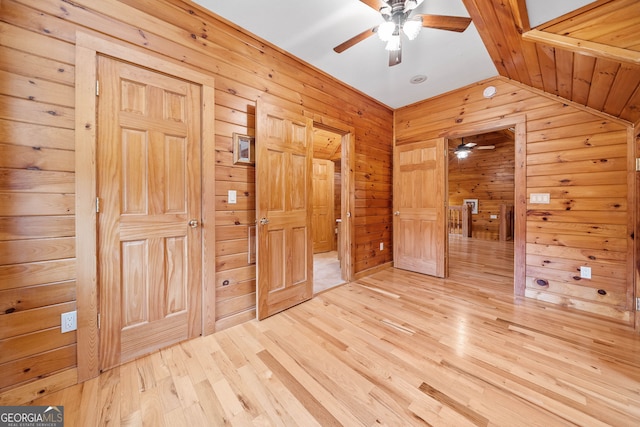 unfurnished bedroom with vaulted ceiling, hardwood / wood-style floors, and wood walls