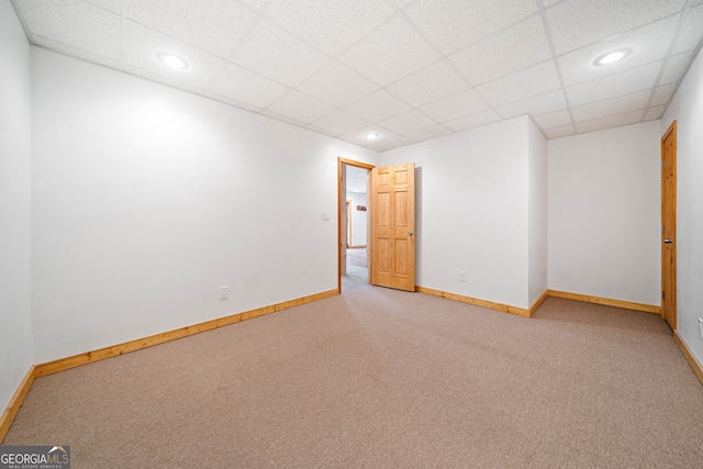 carpeted empty room featuring a drop ceiling