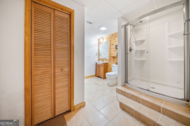 bathroom featuring a drop ceiling, vanity, an enclosed shower, tile patterned flooring, and toilet